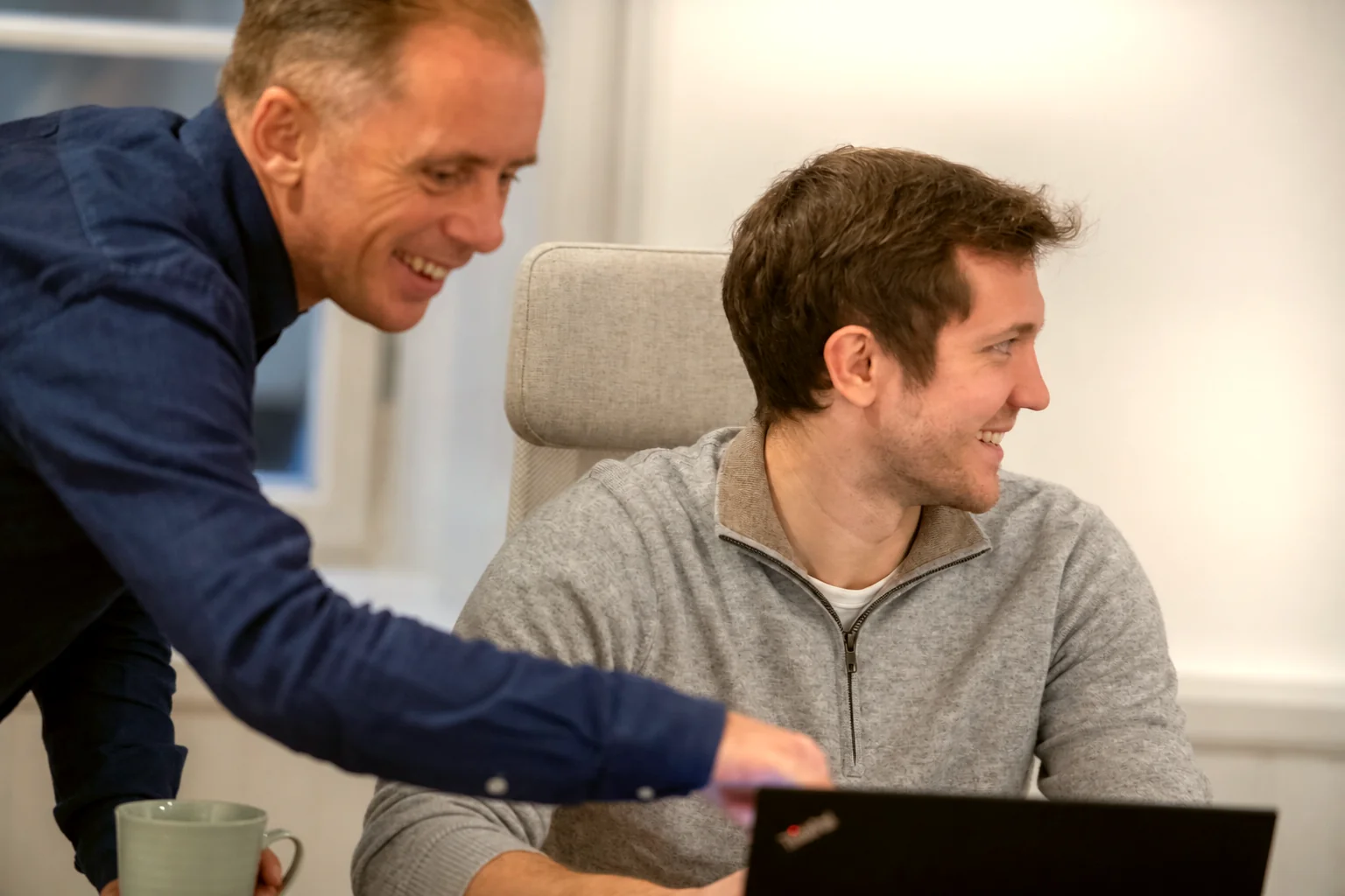 Måns och Johan skrattar tillsammans framför en dator